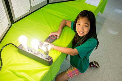 Young girl with light bulb science fair project.